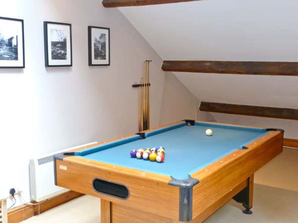 A game room with a pool table and cue sticks at 14 Riverside Walk, Skipton