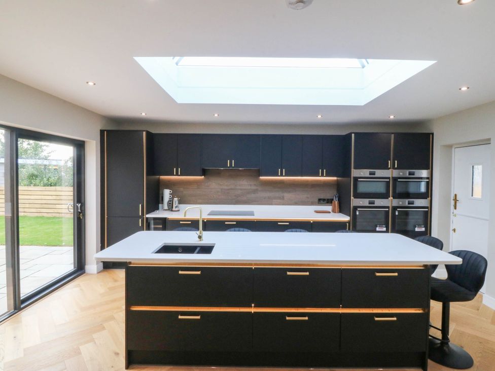 A kitchen with black cabinets and a central island at Angorfa in Pentraeth