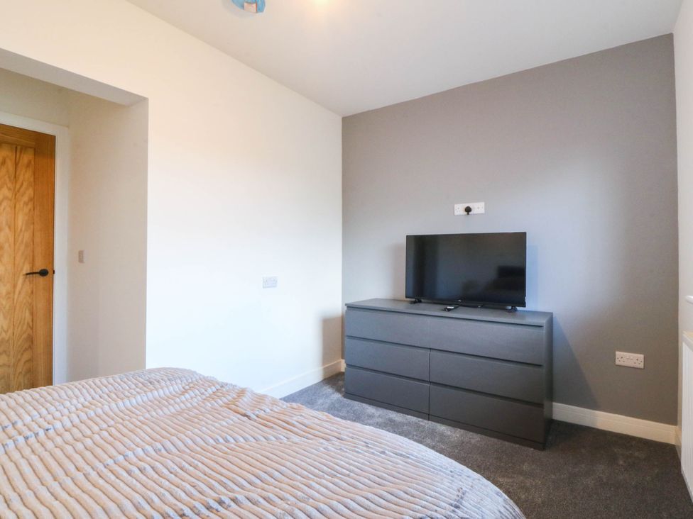 A bedroom with a dresser and television at Angorfa in Pentraeth
