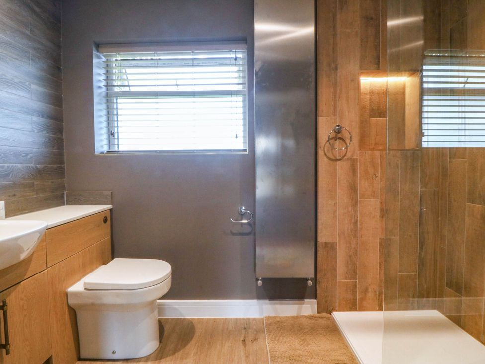 A bathroom with a sink, toilet, and shower at Angorfa in Pentraeth