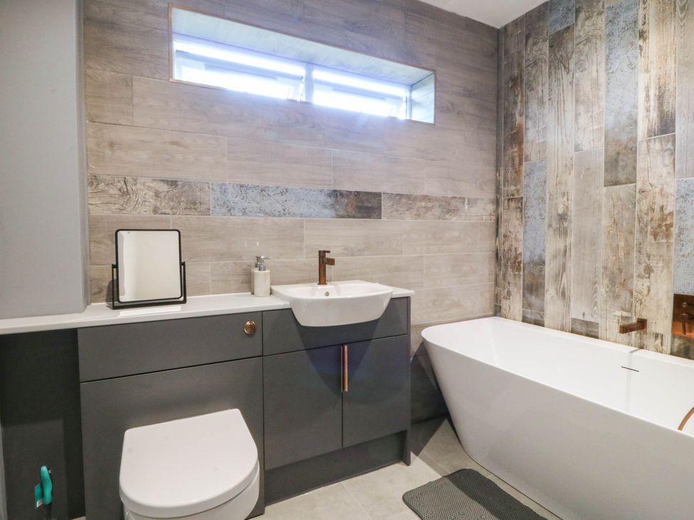 A bathroom with a sink, toilet, and bathtub at Angorfa in Pentraeth