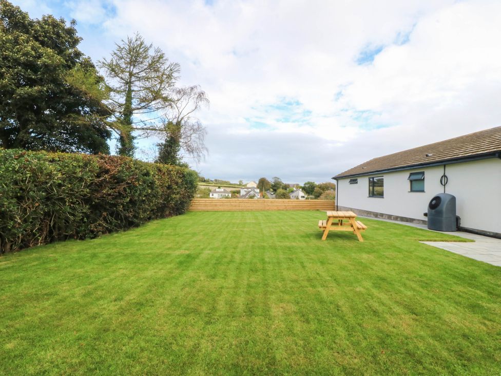 A garden with a table and water butt at Angorfa in Pentraeth