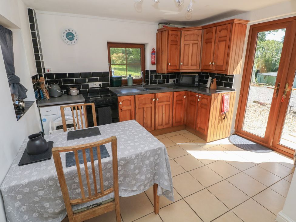 A kitchen with wood cabinets and a table at Tor Cefn Annex in Kidwelly