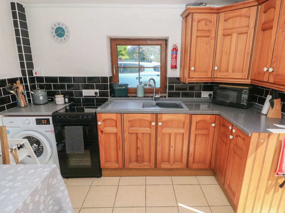 A kitchen with wooden cabinets and appliances at Tor Cefn Annex in Kidwelly
