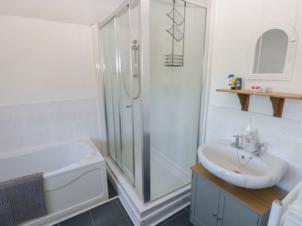 A bathroom featuring a bathtub, shower, and sink at Tor Cefn Annex in Kidwelly