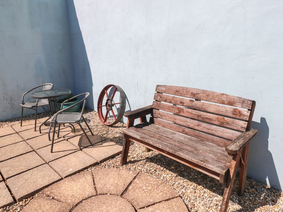 A seating area with a bench and table in a garden at Tor Cefn Annex Kidwelly
