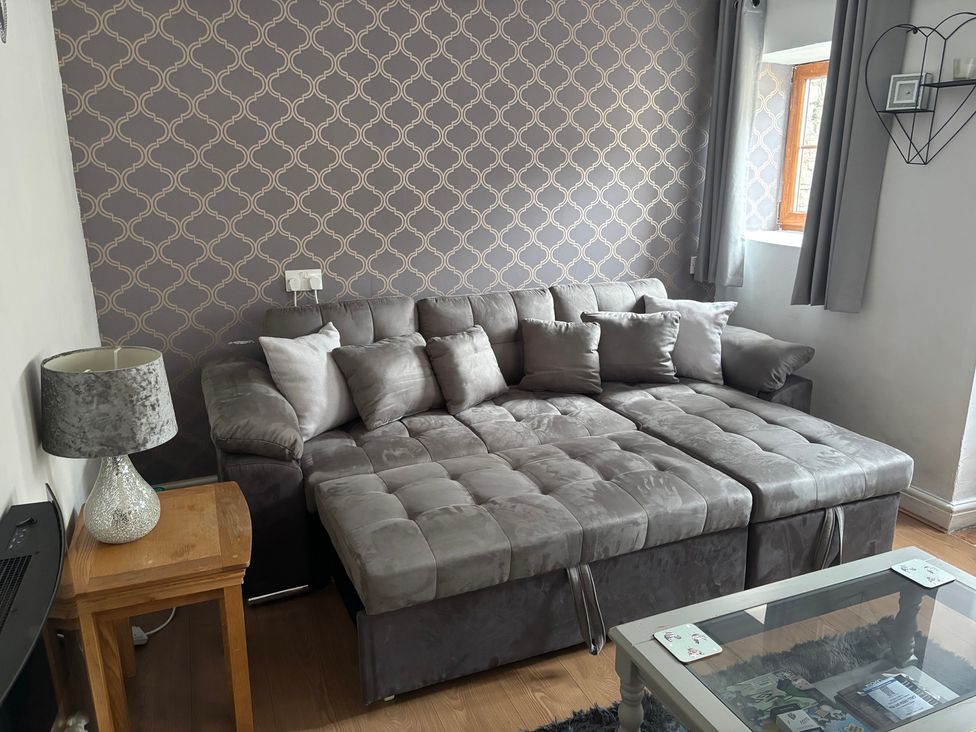 A living room with a sofa and lamp at Tor Cefn near Pont-Henri
