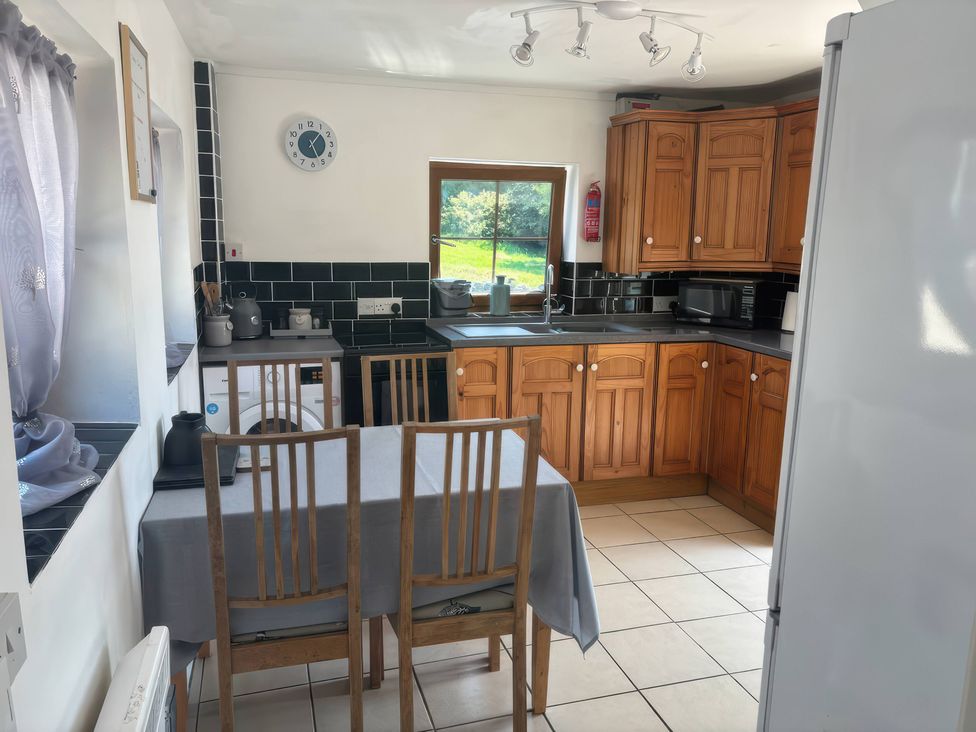 A kitchen with wooden cabinets and a table at Tor Cefn near Pont-Henri