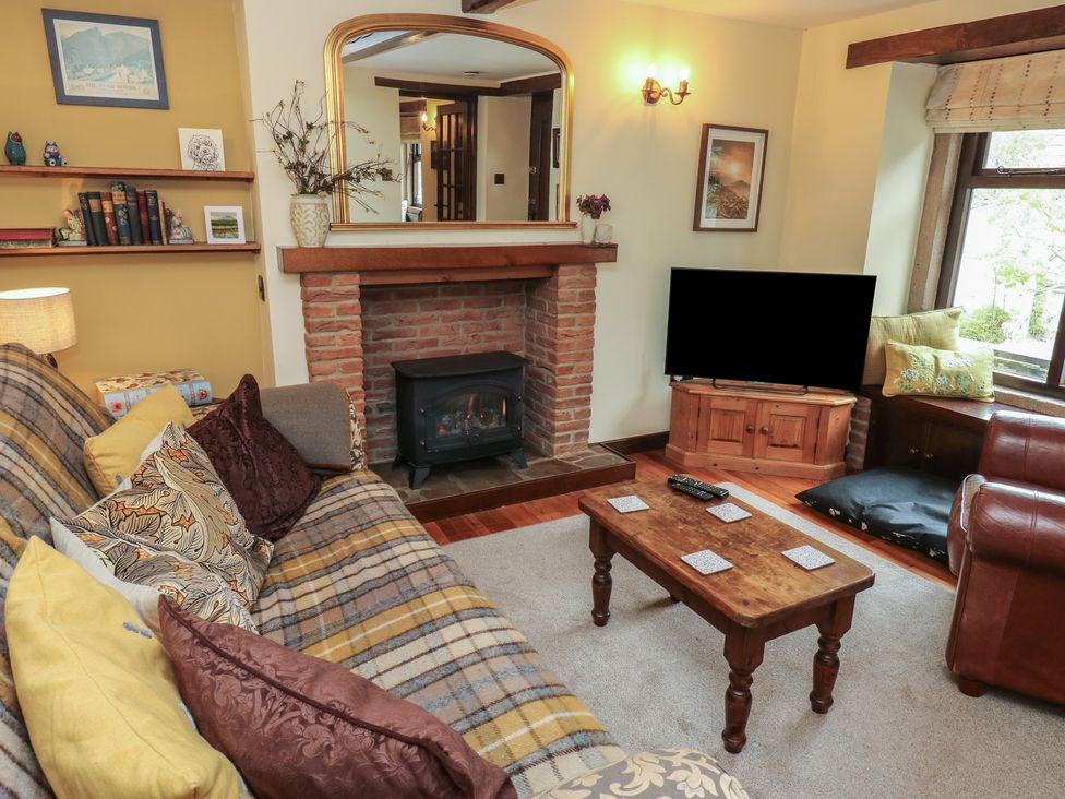 A living room with a fireplace, sofa, coffee table, and TV at Bradshaw House, Hope Valley