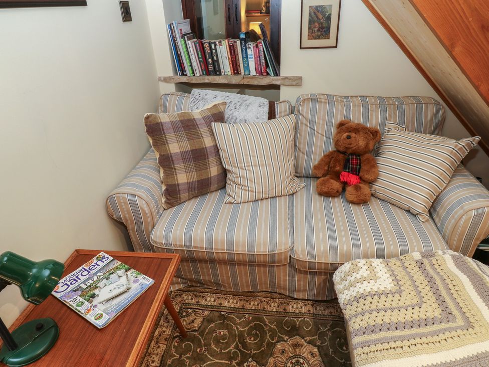 A snug with a striped sofa, bear, and a table with a magazine at Bradshaw House, Hope Valley