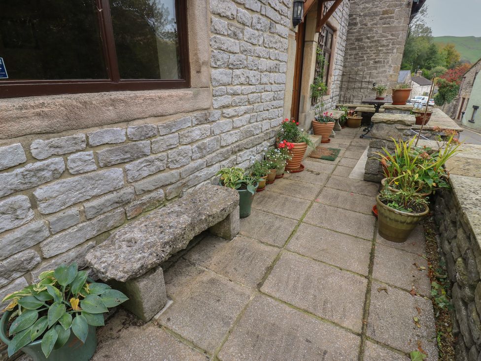 An outdoor area with a stone bench and various potted plants at Bradshaw House in Hope Valley