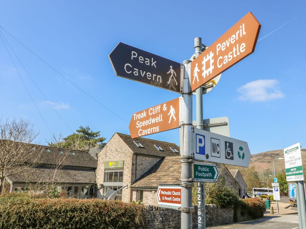 A signpost indicating directions to Peak Cavern and Peveril Castle in Hope Valley