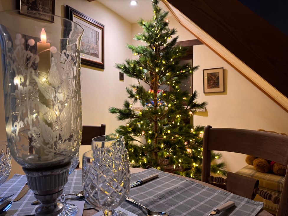 A dining room with a table set for dinner and a Christmas tree at Bradshaw House in Castleton, Peak District