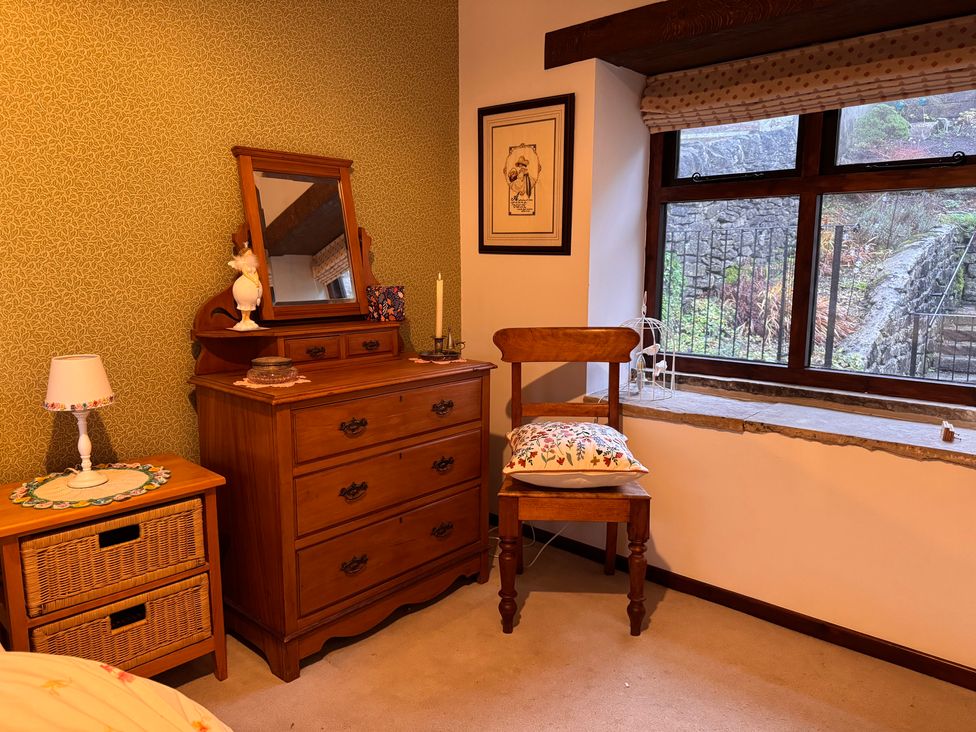 A bedroom with a dresser, mirror, and chair at Bradshaw House, Castleton, Peak District