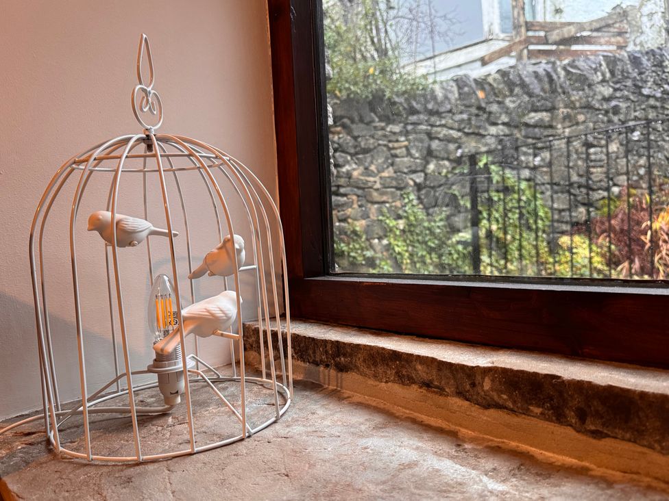 A decorative light cage with birds by a window at Bradshaw House, Castleton, Peak District