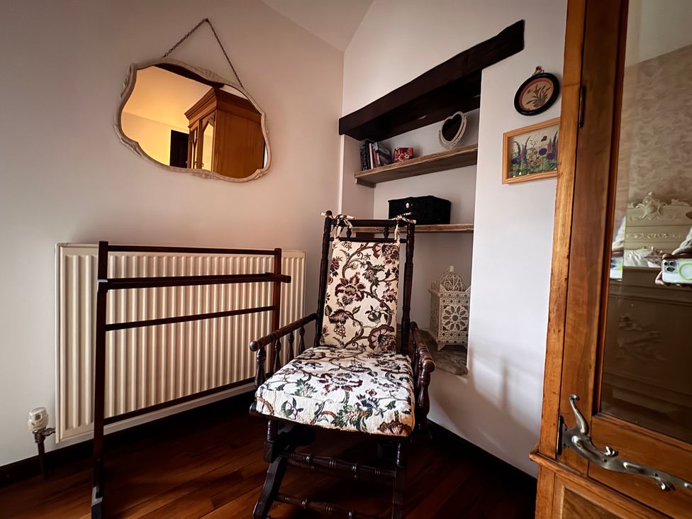 A chair with a mirror and bookshelf in a bedroom at Bradshaw House, Castleton, Peak District