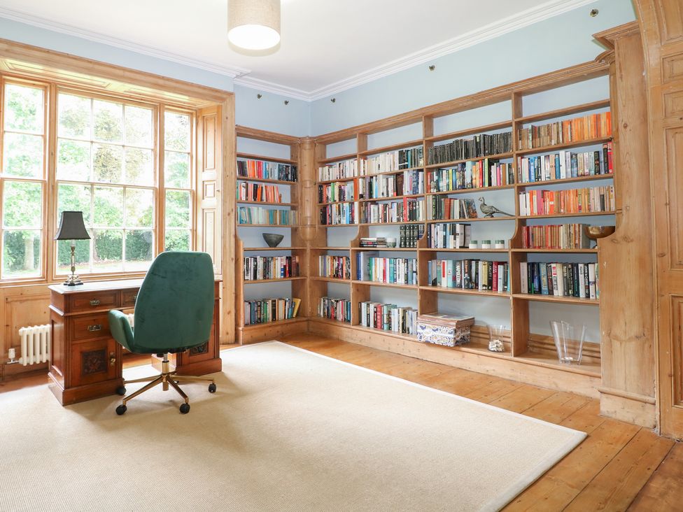 A study with a desk, chair, bookshelf, and window at The Old Vicarage 