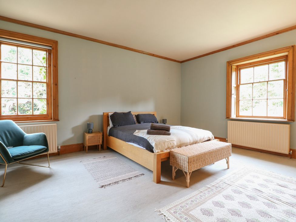 A bedroom with a bed, chair, and windows at Old Vicarage