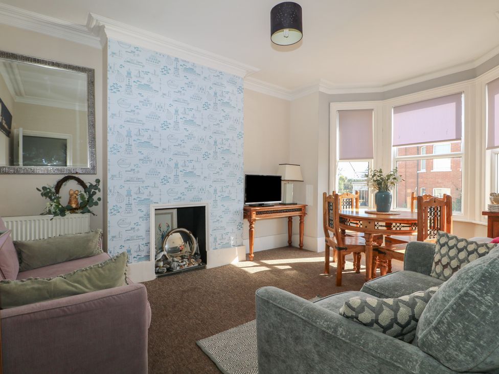 A living room with a sofa and dining table at Pebbles in Eastbourne