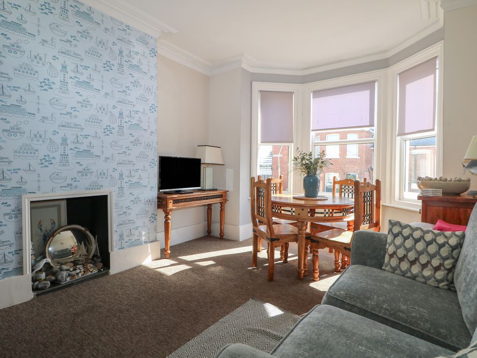 A living room with a dining table and a television at Pebbles in Eastbourne