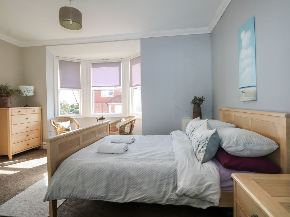 A bedroom with a bed and a dresser with a lamp at Pebbles in Eastbourne