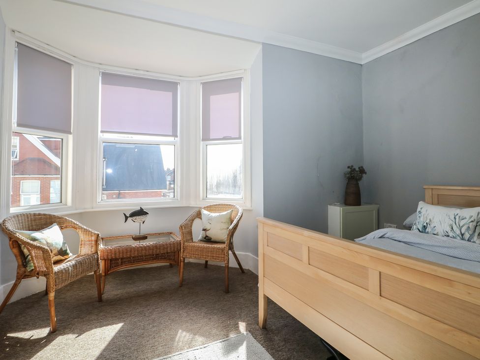 A bedroom featuring a bed, chairs, table, and windows at Pebbles Eastbourne