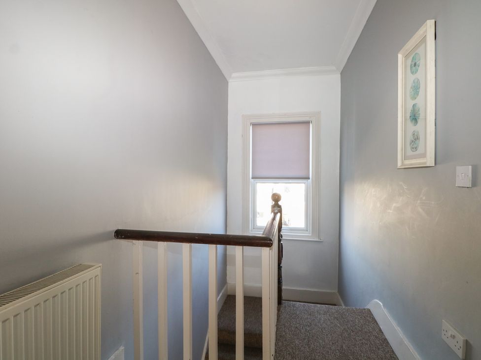 A staircase with a window and radiator in a hallway at Pebbles in Eastbourne