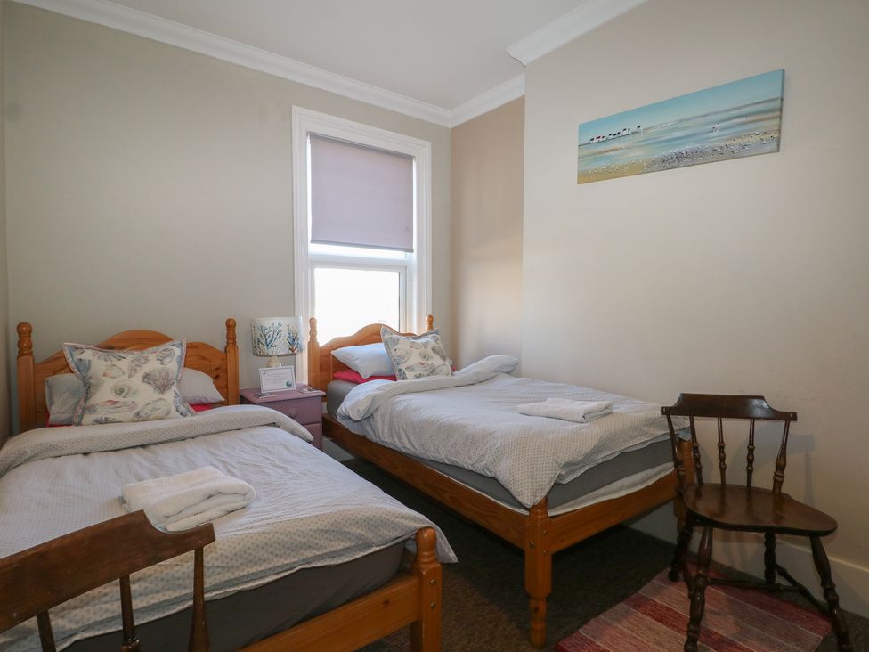 A bedroom with two beds and a chair at Pebbles in Eastbourne