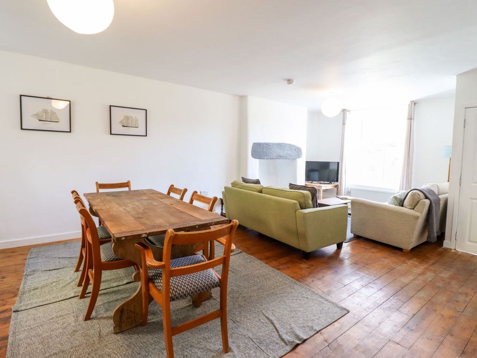 A dining area with a table and chairs next to a living area with sofas at Haulfryn in Dolwyddelan