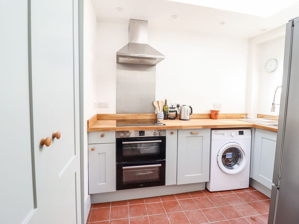 A kitchen featuring an oven, washing machine, and wooden countertop at Haulfryn in Dolwyddelan