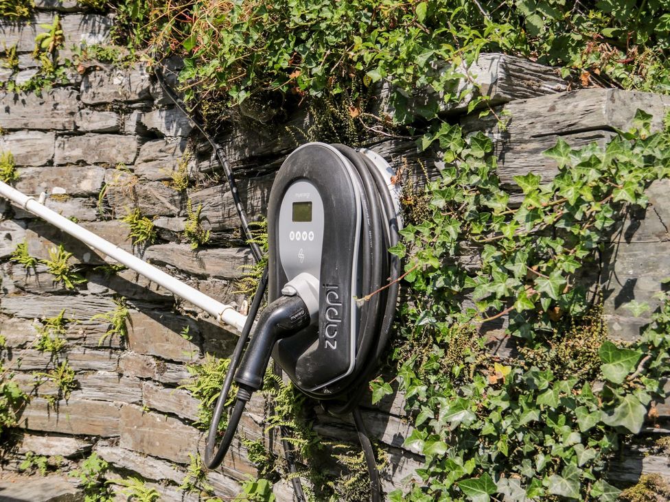 An electric vehicle charger mounted on a stone wall surrounded by ivy at Haulfryn in Dolwyddelan