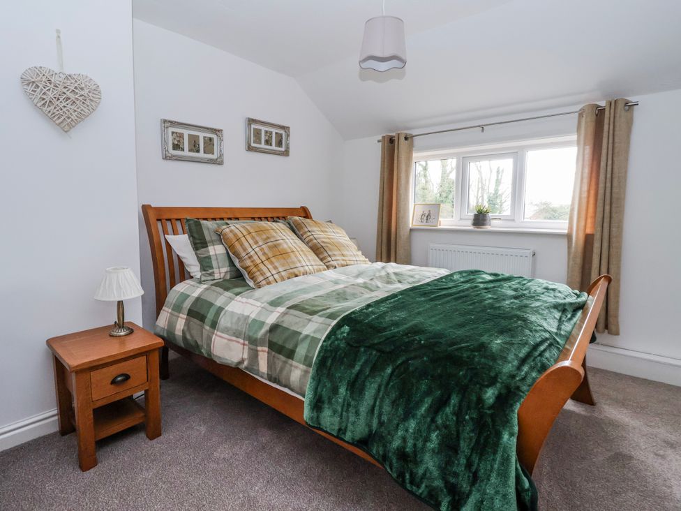 A bedroom with a bed and nightstand at Forget Me Not Cottage in Roos