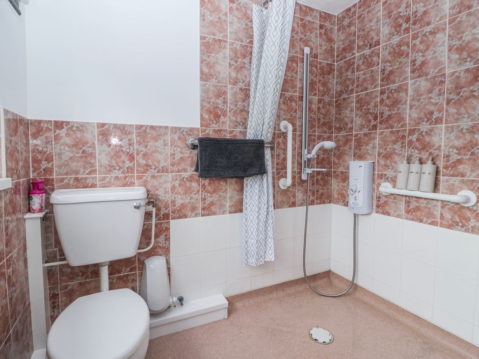 A bathroom featuring a toilet and a shower with grab bars at Forget Me Not Cottage in Roos