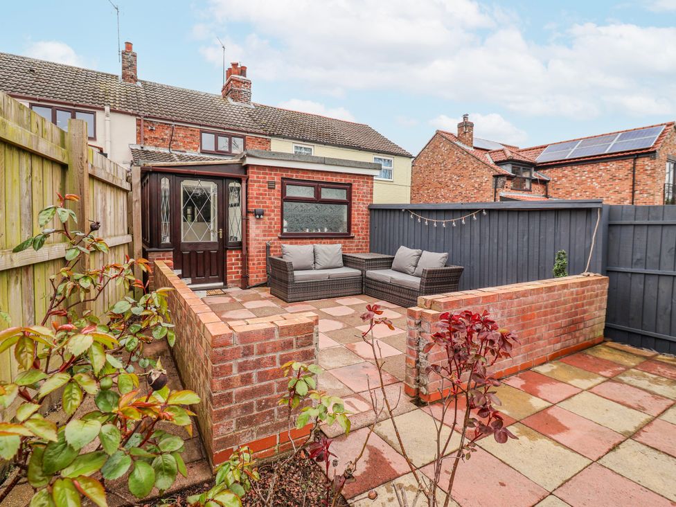 A garden with a sofa and table at Forget Me Not Cottage in Roos