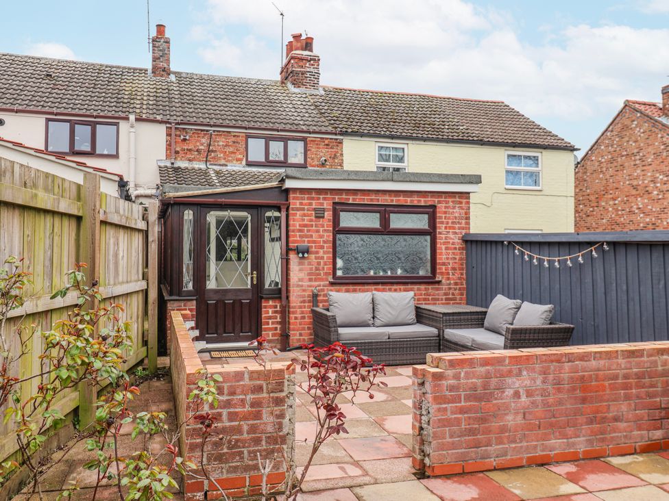 A garden with a seating area and brick wall at Forget Me Not Cottage in Roos