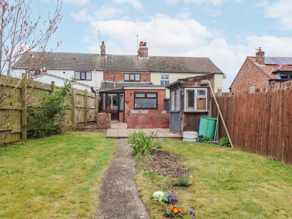 A garden with a pathway and shed at Forget Me Not Cottage in Roos