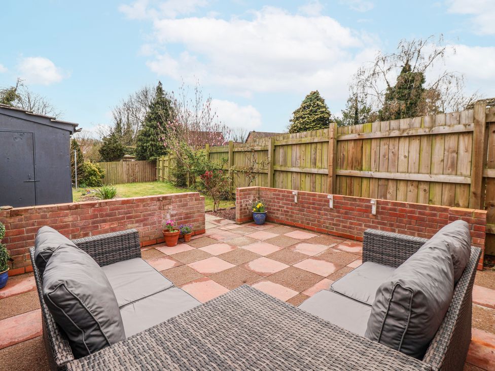 A garden with a patio and sitting furniture at Forget Me Not Cottage in Roos