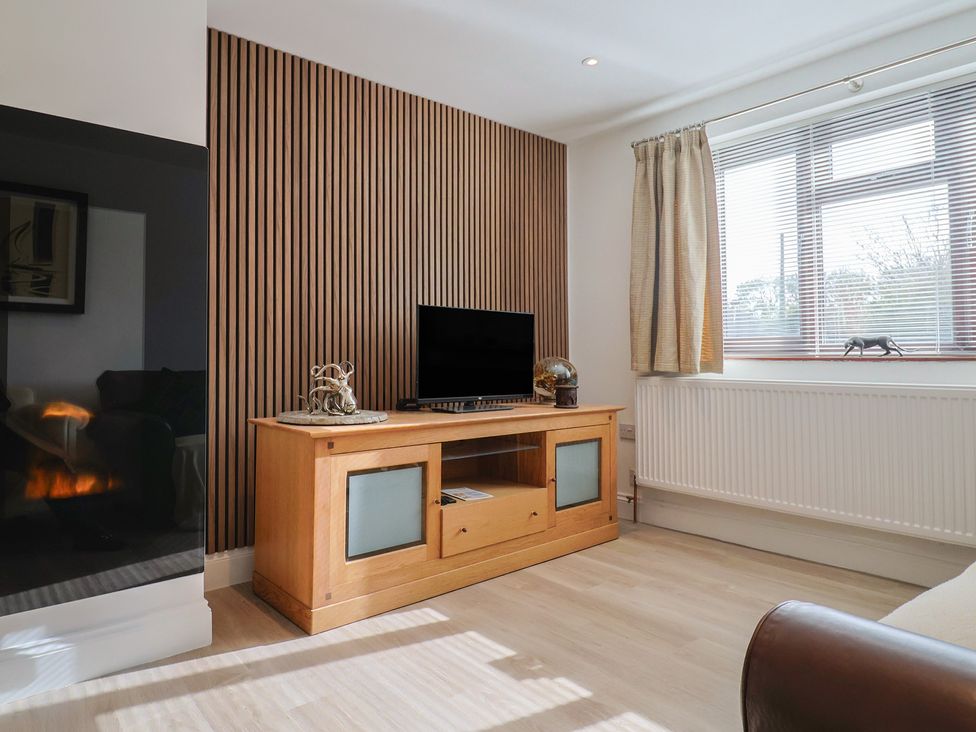 A living room with a television on a cabinet at Arum in Portland Bill