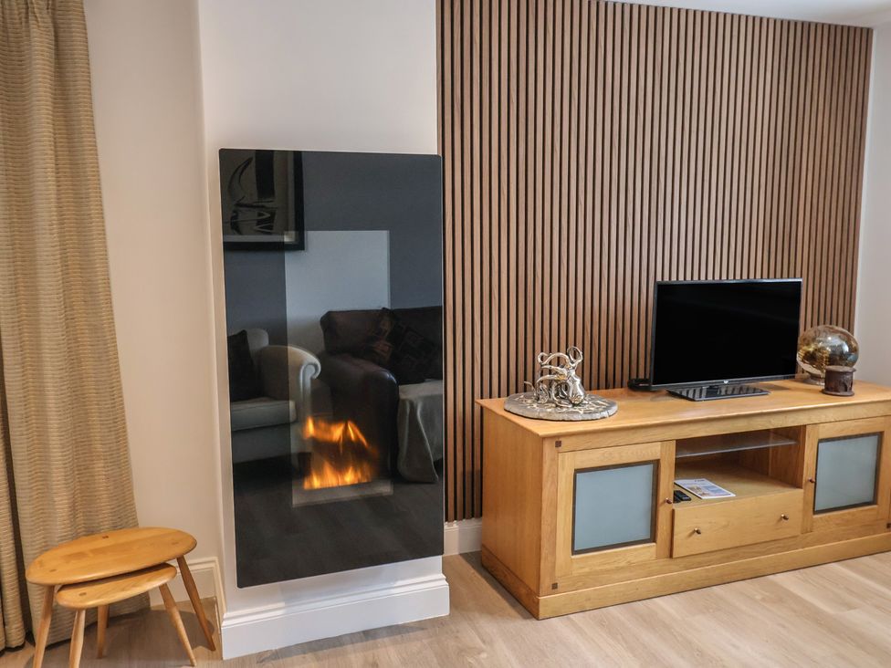 A living room with a fireplace and television at Arum in Portland Bill