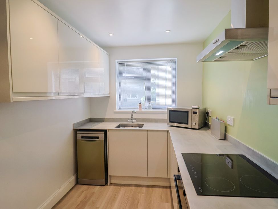 A kitchen with modern appliances and a window at Arum in Portland Bill