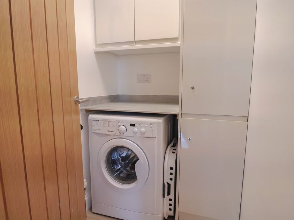 A utility room with a washing machine and cabinets at Arum in Portland Bill