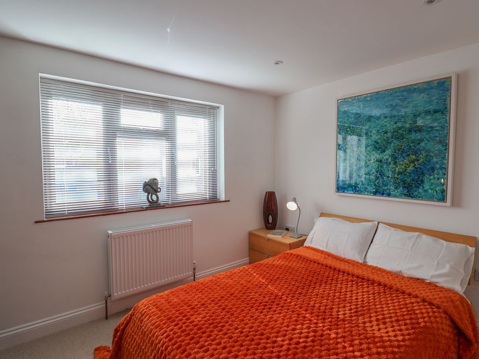 A bedroom with a bed and decorative painting at Arum in Portland Bill