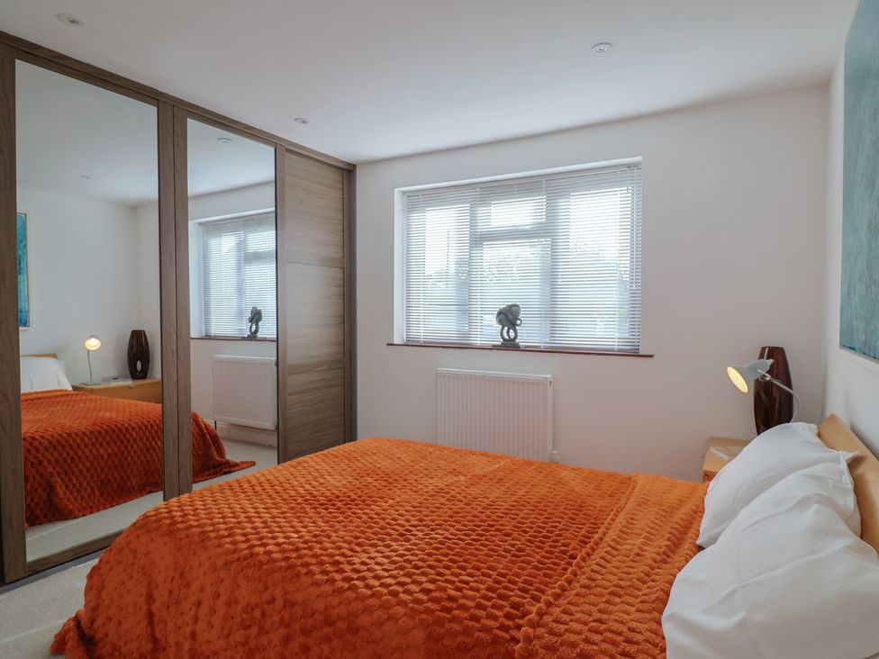 A bedroom with a bed and a mirror at Arum Portland Bill