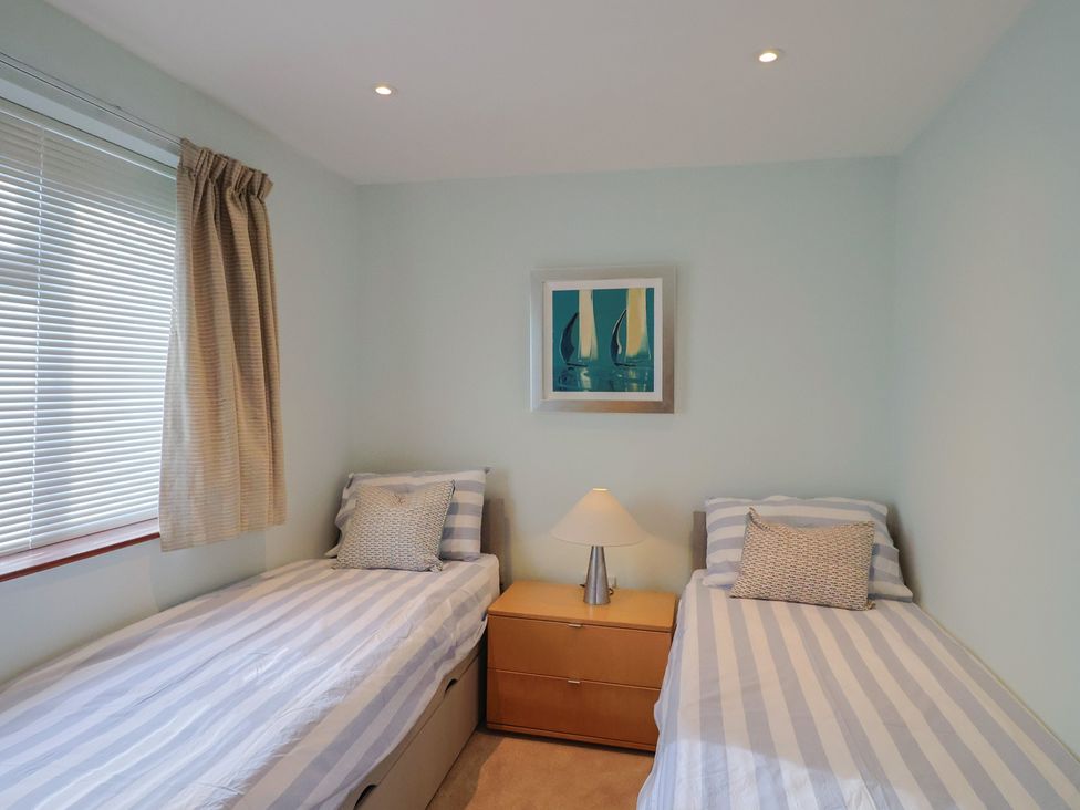 A bedroom with two beds and a lamp at Arum in Portland Bill