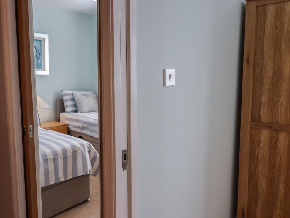 A bedroom with two beds and a bedside table at Arum in Portland Bill