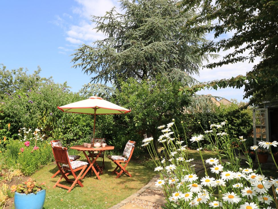 A garden with a table and chairs under an umbrella at Evergreen in Broadway