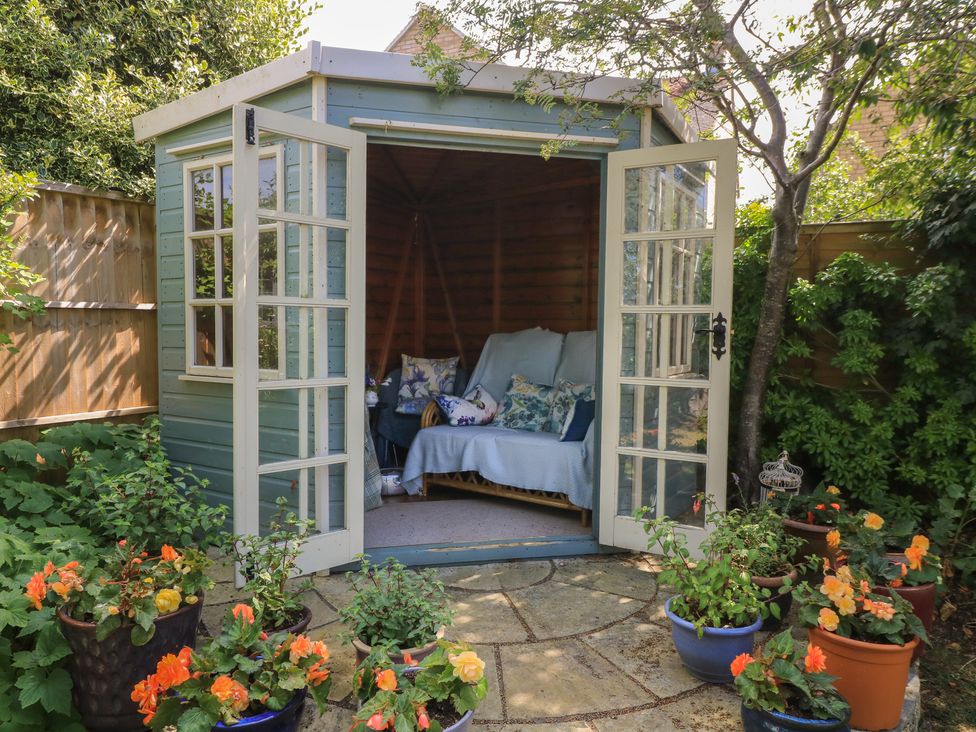 A garden shed with seating and flowers at Evergreen in Broadway