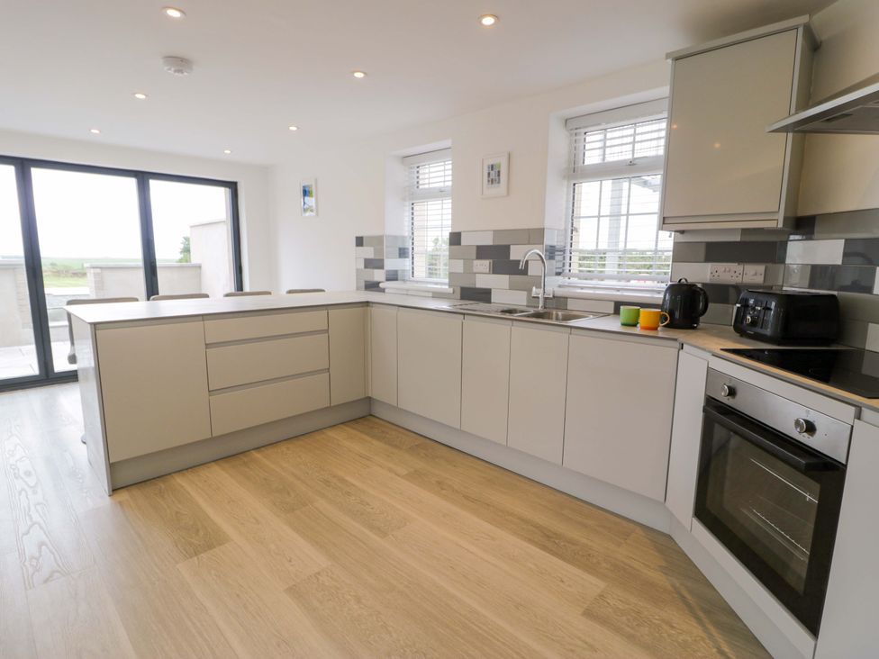 A kitchen with modern cabinets and appliances at Rosemary Cottage 1 Tywyn