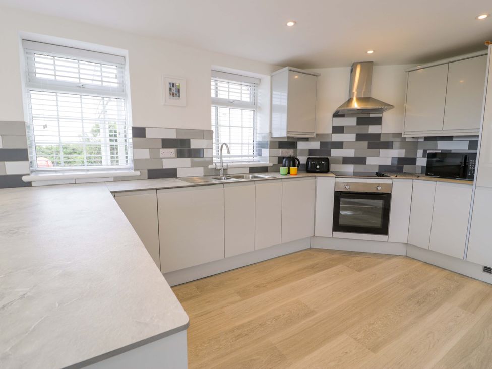 A kitchen with cabinets and appliances at Rosemary Cottage 1 in Tywyn