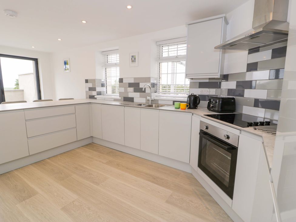 A kitchen with cabinets, sink, stove, and kettle at Rosemary Cottage 1 Tywyn